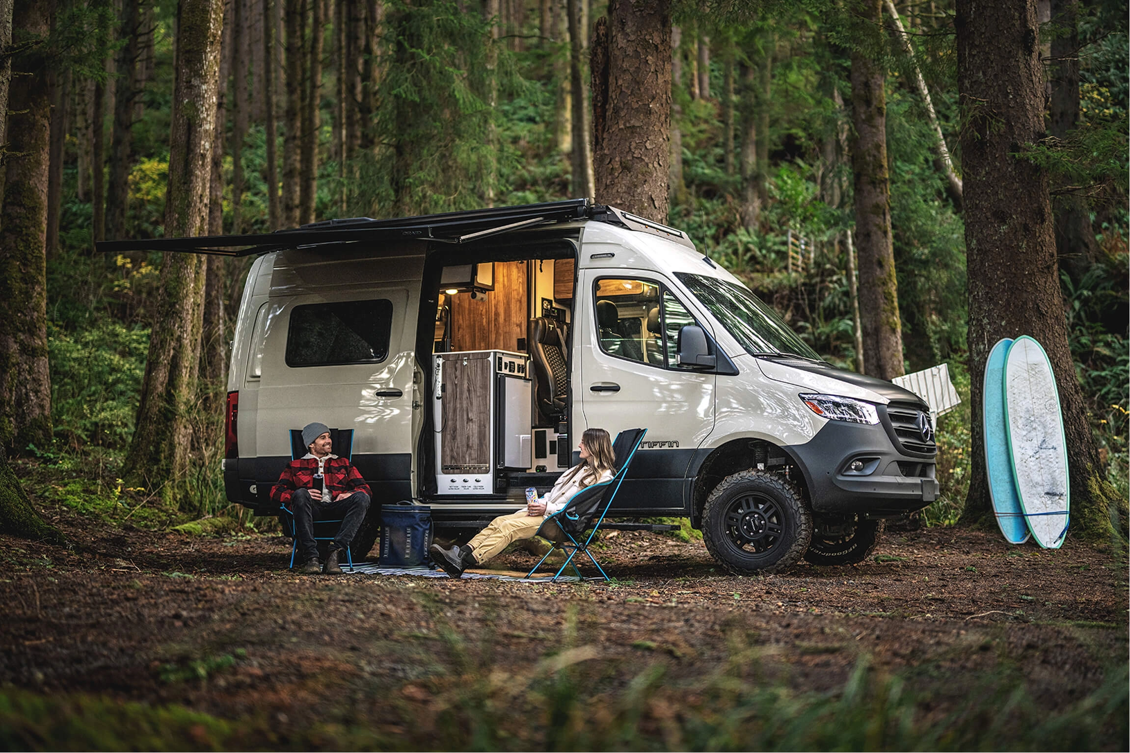 A couple lounging in the woods while camping in their Tiffin motorhome
